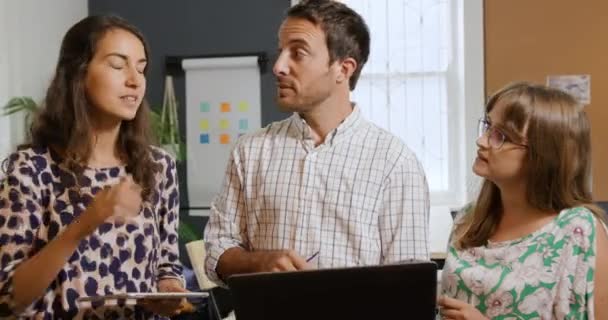 創造的なビジネスのオフィスで働いている百万人の白人男性と2人の女性の正面図 立って 話して ラップトップコンピュータとタブレットを使用しています — ストック動画