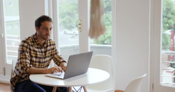 一个快乐的千年白人男子在一家创意企业的办公室里工作 坐在办公桌前 使用笔记本电脑 面带微笑 — 图库视频影像