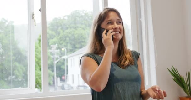 創造的なビジネスのオフィスで働く幸せな100万人の白人女性の正面図 スマートフォンで話す — ストック動画
