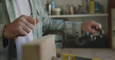 Kafkasyalı bir adamın evdeki bir atölyede ahşap kıskaçla yavaş çekimde Diy 'i çekerken yan görünümü.