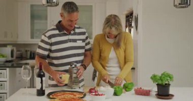 Mutfakta birlikte pizza hazırlayıp gülümseyen, sebze doğrayan kadın ve peynir rendeleyen adam, ağır çekimde