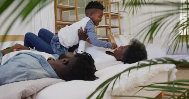 彼らの若い息子と一緒に家のベッドルームに横たわって 彼のお母さんの笑顔に座って 彼女をくすぐるながら 彼女は彼を保持し スローモーション — ストック動画