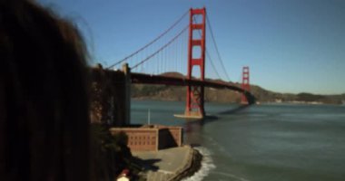 Uzun siyah saçlı bir kadının omuzlarının üzerinden Golden Gate Köprüsü ve San Francisco Körfez Bölgesi 'nin resimlerini çekiyor.