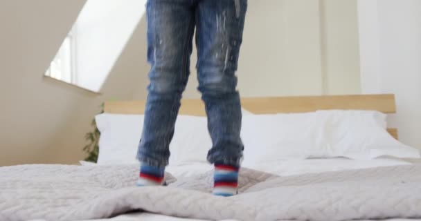 笑顔の若いアフリカ系アメリカ人の少年が家のベッドの上で跳び下がりゆっくりとした動き — ストック動画