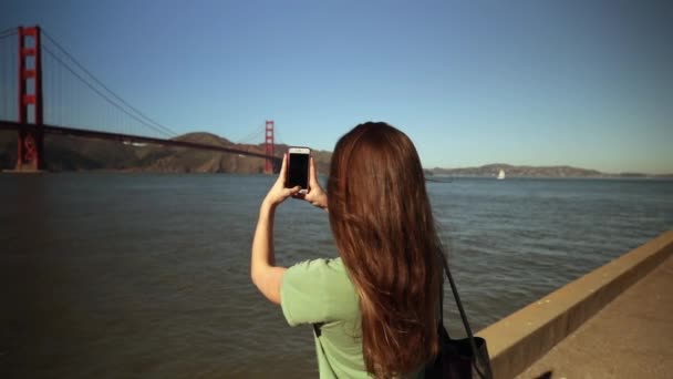 一个有着长长的黑头发的年轻白人妇女站在后视镜下 用智能手机拍摄金门大桥和旧金山湾地区 — 图库视频影像