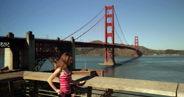 一个有着一头乌黑长发的年轻白人妇女用智能手机与金门大桥和旧金山湾地区合影 — 图库视频影像