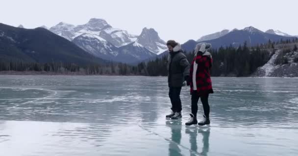 暖かい冬の衣類スケートで100万人の白人のカップルの側のビュー冬の時間に凍った湖で一緒にスケート — ストック動画
