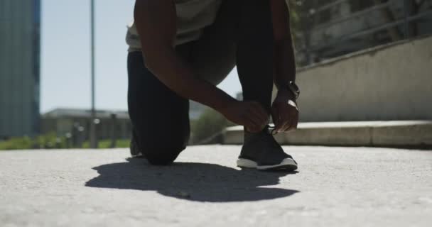 Sección Baja Hombre Afroamericano Con Una Sudadera Sin Mangas Atándose — Vídeo de stock