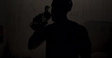 Atletik bir Afrikalı Amerikalının silueti şehrin güneşli bir gününde antrenman yaparken bir köprünün altında duvara yaslanıp su içerken ağır çekimde mola veriyor.