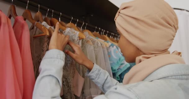 Вид Сбоку Молодую Женщину Смешанной Расы Хиджабе Смотрящую Платья Висящие — стоковое видео