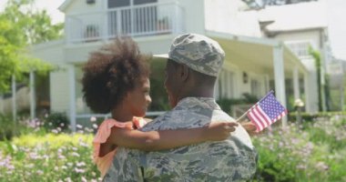 Arka planda, evinin bahçesinde genç bir Afro-Amerikan erkek askerin görüntüsü var. Kameraya bakan, gözleri kapalı ve elinde Amerikan bayrağı, ağır çekimde gülümseyen genç kızını kucaklıyor ve kucaklıyor.