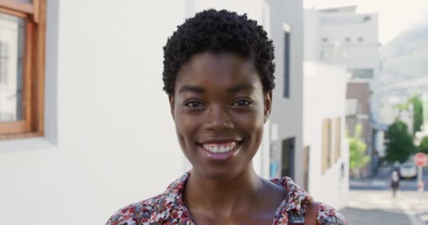 カメラに微笑む晴れた街に立つアフリカ系アメリカ人の若い女性の肖像画スローモーション — ストック動画