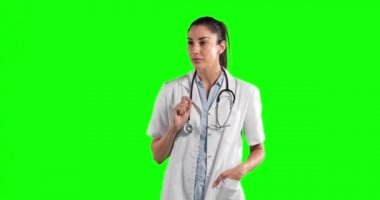 Uzun siyah saçlı, laboratuvar önlüğü ve steteskop giyen beyaz bir kadın doktor yeşil ekran arka planındaki sanal etkileşimli bir ekrana dokunuyor.