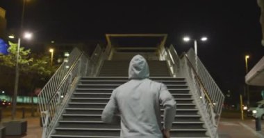 Kafkasyalı bir adamın spor giysisi giydiği arka manzara, gece boyunca şehir sokaklarında egzersiz yapması, eğitimi sırasında üst kata koşması..