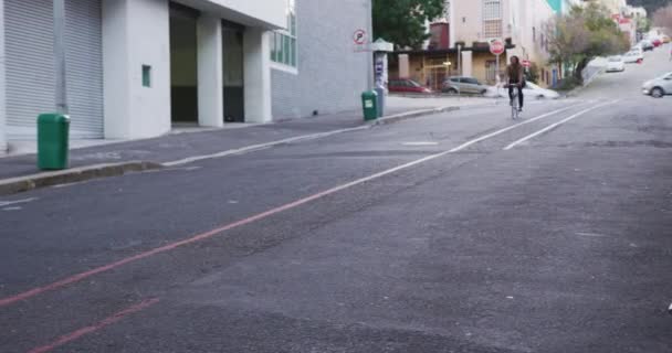 一个白种人穿着格子衬衫 白天在城市街道上走来走去 骑着自行车沿街走去 — 图库视频影像