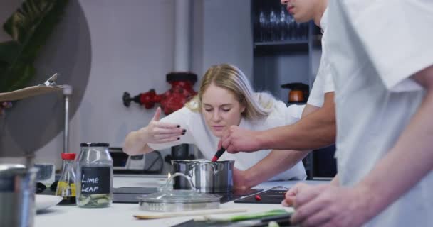 专业的白种人女厨师在餐馆厨房里穿着白色的厨师 准备食物 同事们则慢吞吞地走在前头 — 图库视频影像