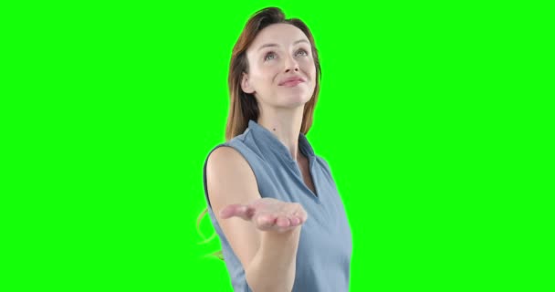 快乐迷人的白种女人 一头棕色的长发 穿着一件聪明的灰色衬衫 胳膊高举着 在她面前分发 呈现出一副绿色背景的虚拟互动画面 — 图库视频影像