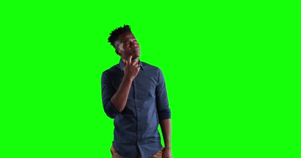 短い暗い髪をした魅力的なアフリカ系アメリカ人男性 暗いシャツを着て 思考と緑の画面の背景に仮想対話型スクリーンを見て — ストック動画