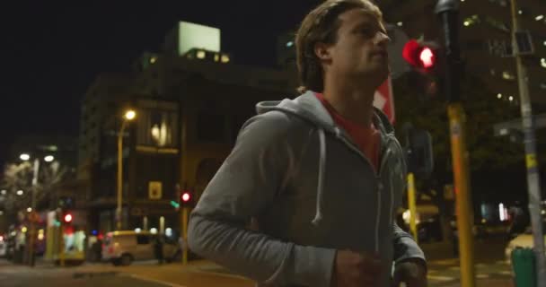 スポーツウェアを身に着けている白人男性 夜の間に街の通りで運動 ウォーミングアップと彼の訓練の前に詐欺 — ストック動画