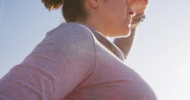 Beyaz tenli çekici kadın güneşli bir günde kumsalda egzersiz yapmaktan zevk alıyor. Yoga yapıyor, gözlerini kaçırıyor, güneşten koruyor.