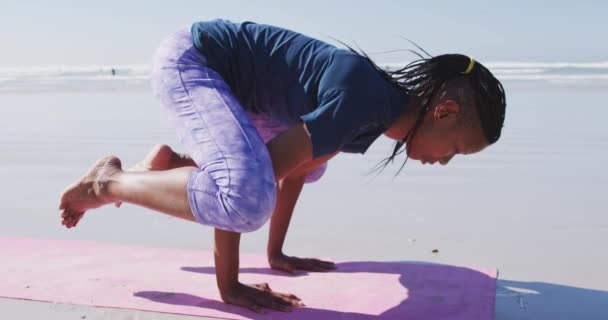 在阳光充足的海滩上 身穿运动服 练习瑜伽 手握瑜伽姿势的美国黑人美女 — 图库视频影像