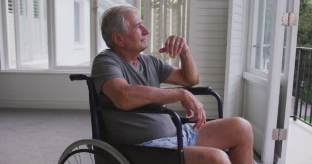 上了年纪的高加索人呆在家里 在禽流感流行期间自我隔离 坐在轮椅上 凝视着窗户 动作缓慢 — 图库视频影像