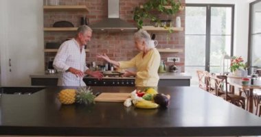 Üst düzey Kafkasyalı çift evde birlikte vakit geçiriyorlar, Coronavirus covid 19 salgını sırasında karantinada kendilerini izole ediyorlar, mutfakta dans ediyorlar, yavaş çekim.