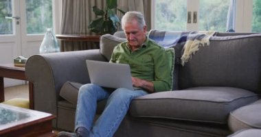 Üst düzey beyaz adam evde vakit geçiriyor. Coronavirus covid 19 salgını sırasında karantinada tek başına. Dizüstü bilgisayar kullanıyor.