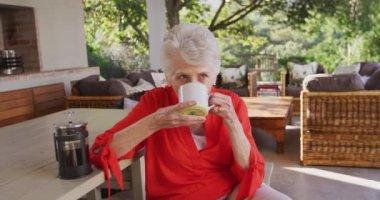 Beyaz kadın bahçesinde vakit geçiriyor. Koronavirüs salgını sırasında karantinada tek başına. Elinde bardak ve içki, ağır çekim.