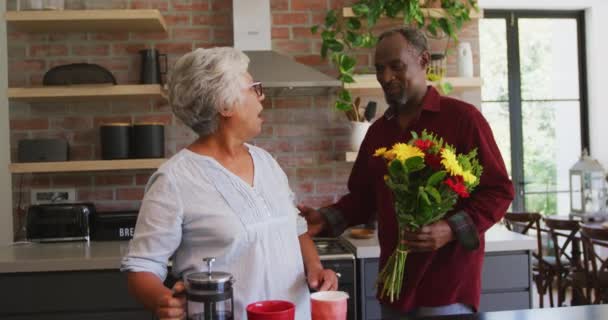 老年非洲裔美国男人和混血女人呆在家里 在考罗纳维病毒流行期间自我隔离 男人给女人送花 动作缓慢 — 图库视频影像