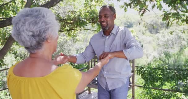 シニアアフリカ系アメリカ人男性と混合人種の女性は自宅で時間を過ごします コロナウイルスの流行の間に隔離されたロックダウンで自己隔離 彼らの庭で踊ります スローモーション — ストック動画