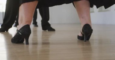 Düşük ırk erkek dans hocasının dans stüdyosunda dans dersi alması, yavaş çekimde bir grup Kafkas yaşlıya dans adımları göstermesi.