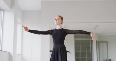 Beyaz kadın balerin siyah elbiseler giyer, dans dersleri sırasında dans kursunda yavaş çekimde dans eder..