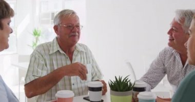 Bir grup mutlu son sınıf erkek ve bayan arkadaş bir masada oturup dans sınıfından önce sosyalleşiyorlar, yavaş çekimde çay ve kahve içip sohbet ediyorlar.