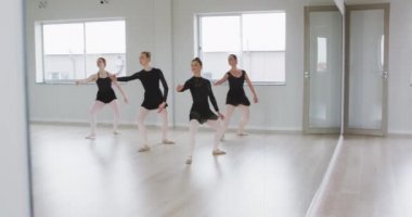 Beyaz kadın dört dansçı, siyah tricotlar giyip, yavaş çekimde, parlak bir stüdyoda, bale dersleri sırasında dans ediyorlar..