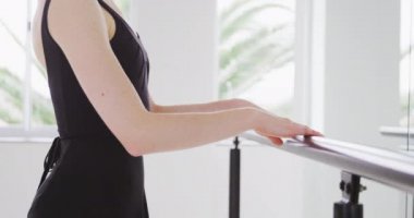 Beyaz kadın balerin, siyah tricot giyerek dans kursuna hazırlanıyor. Ayna karşısında ağır çekimde dans kursuna hazırlanıyor..