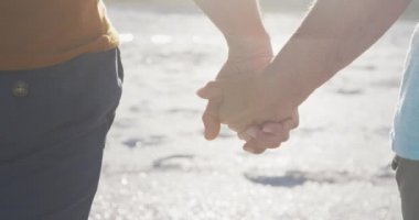 Yaz Sahil Tatili. Güneşli bir günde kumsalda yürüyüp el ele tutuşan, kıdemli beyaz çifti yakından takip edin.