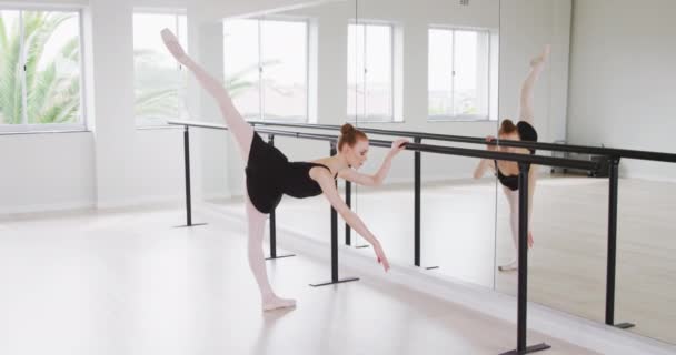 黒の三重奏を身に着けている白人女性バレエダンサー 明るいスタジオでダンスクラスの準備 鏡で伸ばし スローモーションで — ストック動画