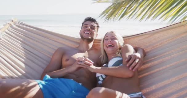 Casal Caucasiano Desfrutando Tempo Praia Deitado Uma Rede Abraçando Sorrindo — Vídeo de Stock