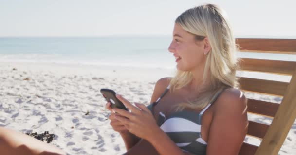 Mulher Caucasiana Desfrutando Tempo Praia Sentada Uma Espreguiçadeira Usando Seu — Vídeo de Stock