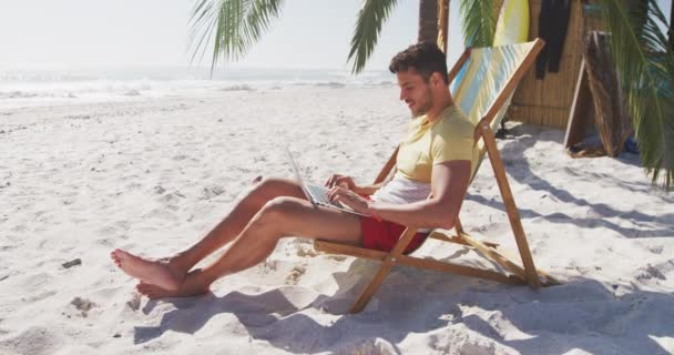 Kaukázusi Férfi Élvezi Időt Strandon Napozóágyon Használja Laptopját Egy Napsütéses — Stock videók