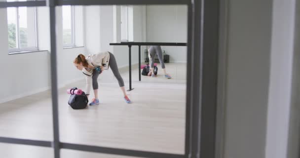 スポーツウェアを着た白人女性バレエダンサー スタジオを歩き スローモーションでスポーツバッグを持っている — ストック動画