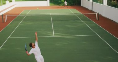 Beyaz tenli, beyaz tenli, beyaz tenli, güneşli bir günde tenis oynayan, tenis raketi tutan, biri yavaş çekimde topa vuran bir beyaz ırk..