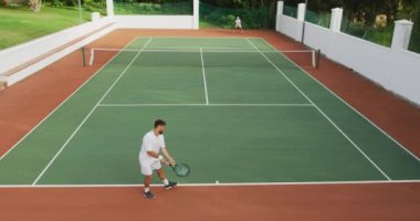 Beyaz tenli, beyaz tenli, beyaz tenli, güneşli bir günde tenis oynayan, tenis raketi tutan, biri yavaş çekimde topa vuran bir beyaz ırk..