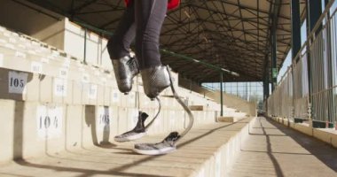 Açık hava spor stadyumunda protez bacaklı, engelli bir erkek sporcunun yavaş çekimde bacaklarını kontrol etmesi.