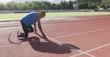 Formda, engelli, protez bacaklı erkek sporcu açık hava spor stadyumunda antrenman sırasında yavaş çekimde bir yarış başlatıyor.