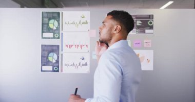 Yaratıcı bir iş yerindeki Mixedrace işadamı, akıllı telefonla konuşuyor, ağır çekimde. İş adamları ve iş arkadaşları yoğun bir kreatif ofiste.