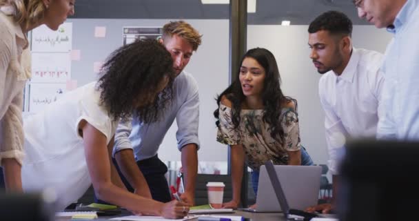 Groupe multi-ethnique de collègues d'affaires au bureau d'une entreprise créative, assis dans une réunion discutant du travail, au ralenti. Des gens d'affaires et des collègues de travail dans un bureau de création occupé.