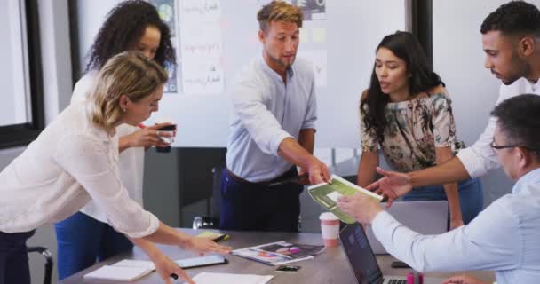Groupe multi-ethnique de collègues d'affaires au bureau d'une entreprise créative, assis dans une réunion discutant du travail, au ralenti. Des gens d'affaires et des collègues de travail dans un bureau de création occupé.