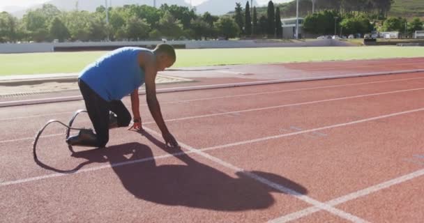 トレーニング中のレースを開始し 屋外スポーツ競技場でランニングトラック上の義肢を持つフィット 無効混合レース男性選手 スローモーションで — ストック動画